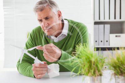 Casual businessman looking at model wind turbines in his office